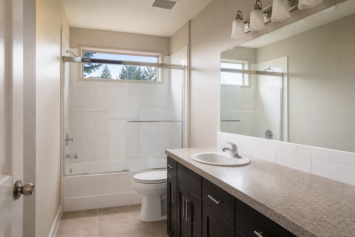 A clean empty rental bathroom in Spokane with descaled shower glass, polished fixtures, and a spotless tub